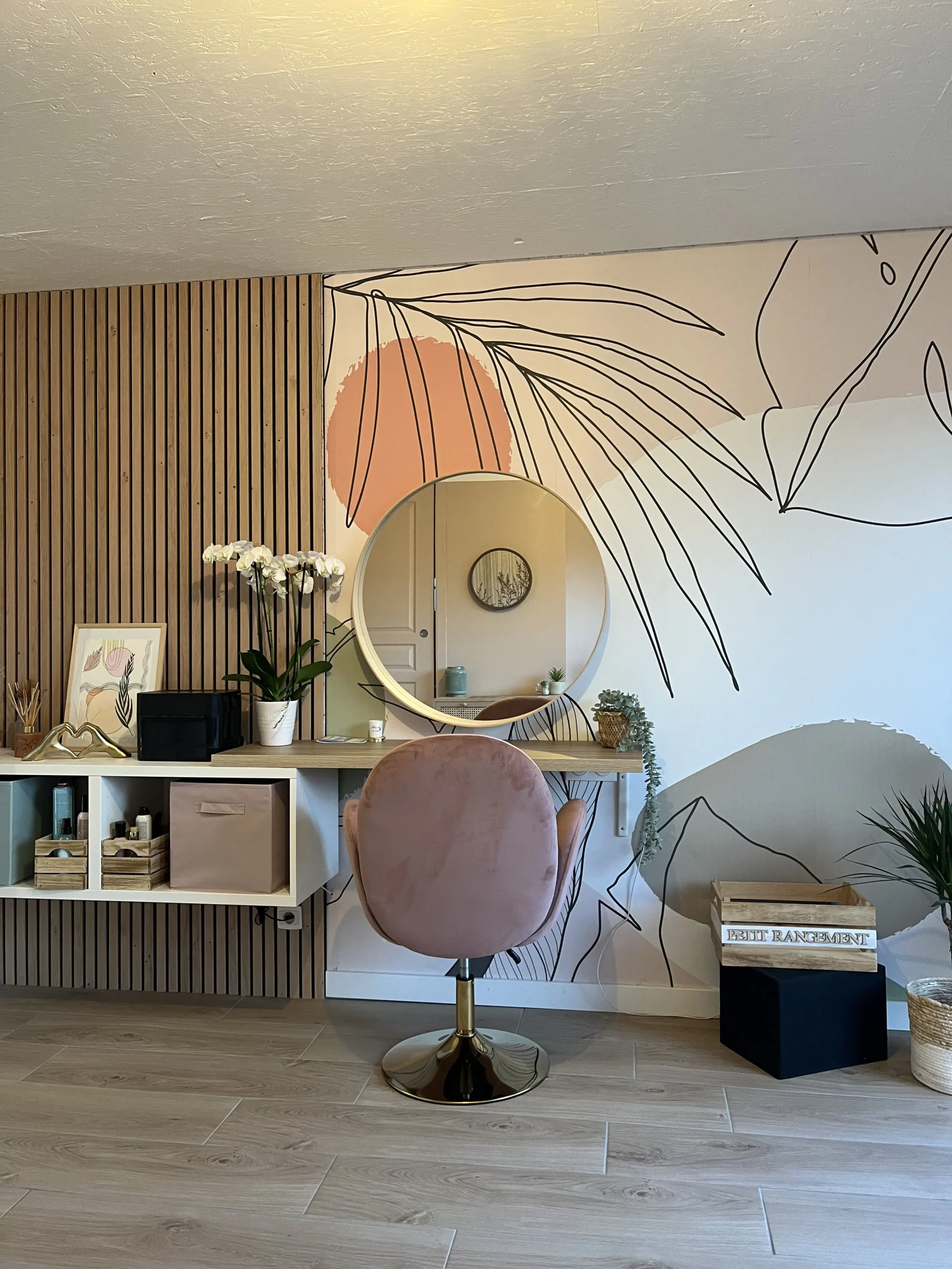 décoration d'un salon de coiffure miroir fauteuil mur de tasseaux de bois et papier peint végétal rose